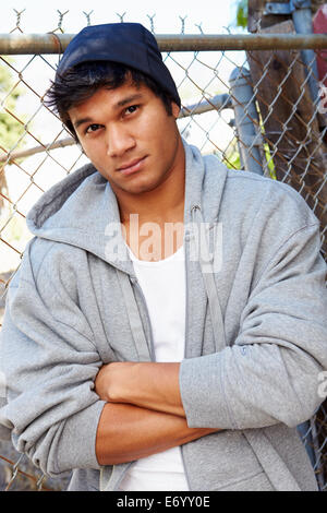 Portrait Of Young Man In Urban Setting Standing By Fence Stock Photo