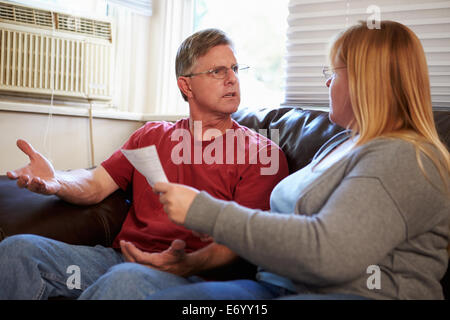 Worried Couple Sitting On Sofa Arguing About Bills