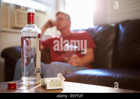 Man Sitting On Sofa With Bottle Of Vodka And Cigarettes Stock Photo