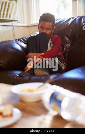 Unhappy Boy Sitting On Sofa At Home Stock Photo