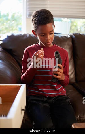 Boy Playing With Parent's Gun He Has Found At Home Stock Photo