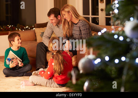 Family Exchanging Gifts By Christmas Tree Stock Photo