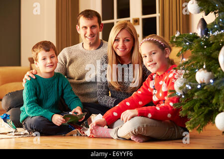 Family Unwrapping Gifts By Christmas Tree Stock Photo