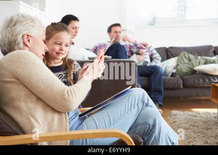 Grandmother And Granddaughter Using Mobile Phone Together Stock Photo