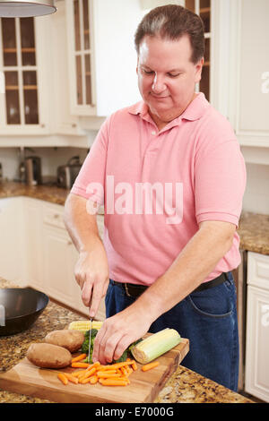 Overweight Man Preparing Vegetables in Kitchen Stock Photo