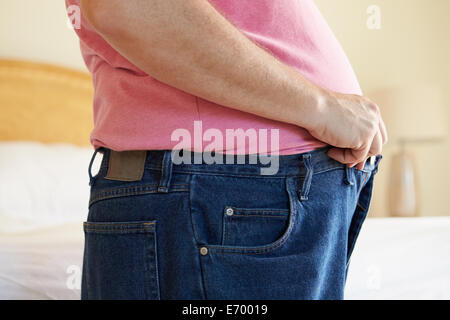 Fat man trying to put on pants. Big Paunch Stock Photo - Alamy