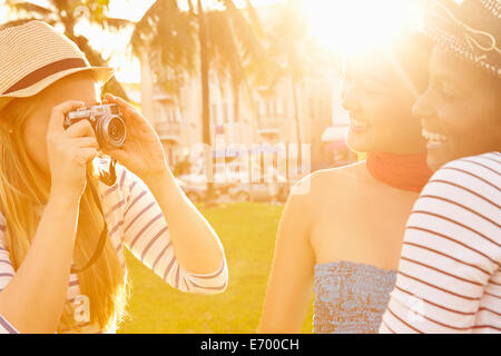 Female Friends Taking Photographs Of Each Other In Park Stock Photo