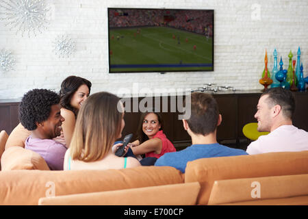Group Of Friends Sitting On Sofa Watching Soccer Together Stock Photo
