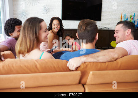 Group Of Friends Sitting On Sofa Watching TV Together Stock Photo