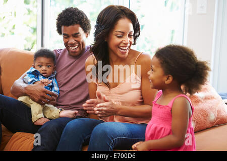 Young Family Relaxing On Sofa Together Stock Photo