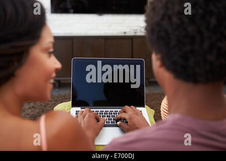 Rear View Of Couple Sitting On Sofa Using Laptop Stock Photo