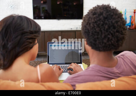 Rear View Of Couple Using Online Banking On Laptop Stock Photo