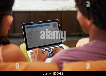Rear View Of Couple Using Online Banking On Laptop Stock Photo