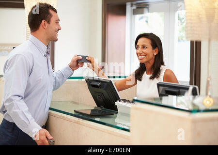 Man Checking In At Hotel Reception Stock Photo