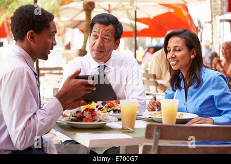 Three Businesspeople Having Meeting In Outdoor Restaurant Stock Photo