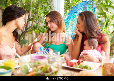 Depressed Mother With Baby Talking To Friends Stock Photo