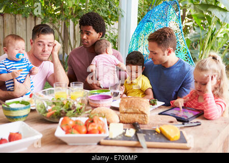 Depressed Father With Baby Talking To Friends Stock Photo