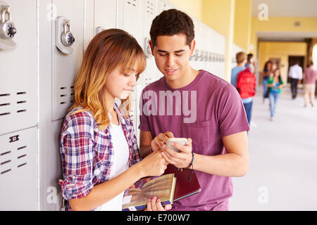 High School Students By Lockers Looking At Mobile Phone Stock Photo