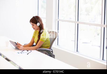 Woman Using Digital Tablet And Headphones In Design Studio Stock Photo