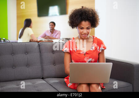 Woman Taking A Break Working On Sofa In Design Studio Stock Photo