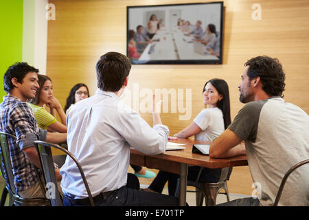 Designers Sitting Around Table In Meeting Looking At Screen Stock Photo
