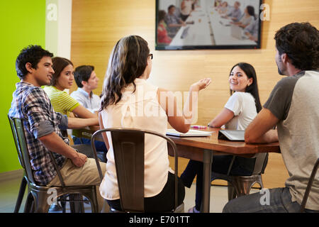 Designers Sitting Around Table In Meeting Looking At Screen Stock Photo