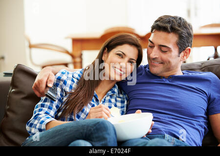 Couple Sitting On Sofa Watching TV Together Stock Photo