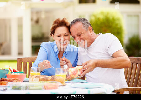 Senior Couple Enjoying Meal In Garden Together Stock Photo
