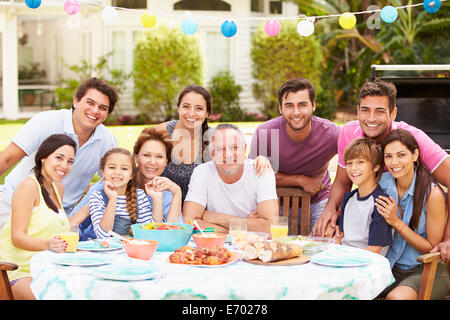 Multi Generation Family Enjoying Meal In Garden Together Stock Photo