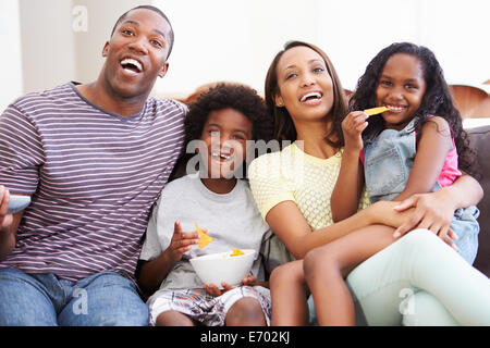 Family Sitting On Sofa Watching TV Together Stock Photo