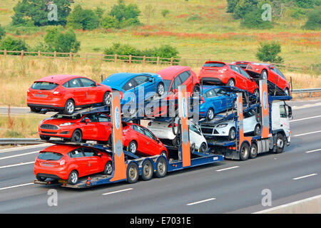 Ford motor company lorry truck car delivery transporter trailer loaded with eleven new red white & blue cars driving on m25 motorway Essex England UK Stock Photo