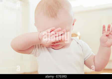 Close up of tired baby boy with hand covering eyes Stock Photo