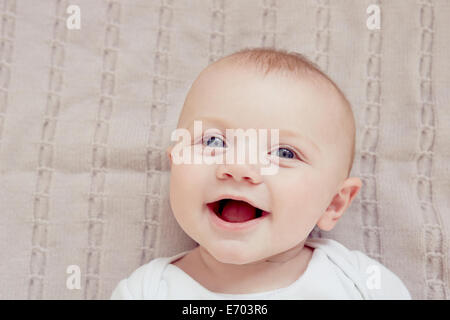 Close up portrait of smiling baby boy lying on blanket Stock Photo