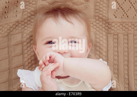 Close up portrait of smiling baby girl lying on blanket Stock Photo