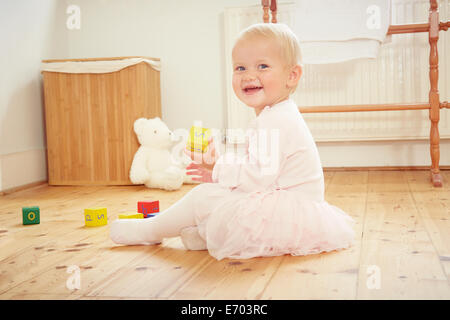 Portrait of smiling baby girl playing on floor with building blocks Stock Photo