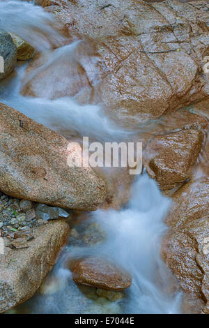 Water rushes across stone, smoothing and shaping the rock, carving a path downward Stock Photo