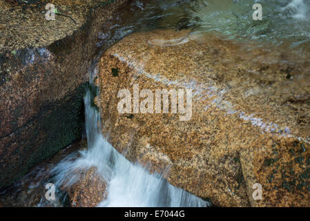 Water rushes across stone, smoothing and shaping the rock, carving a path downward Stock Photo