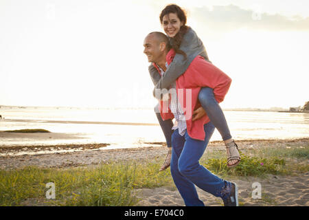 Man giving piggyback ride to woman on beach
