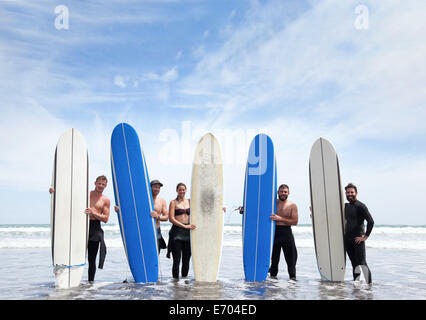 Group portrait of male and female surfer friends standing in sea with surfboards