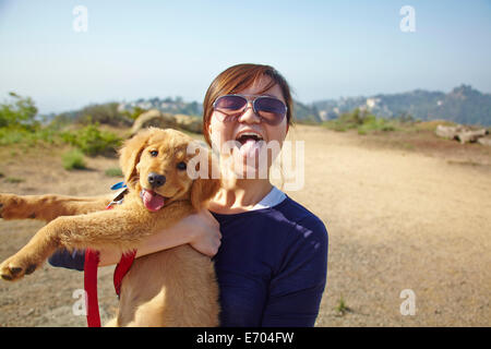 Young woman holding labrador puppy, tongues out Stock Photo