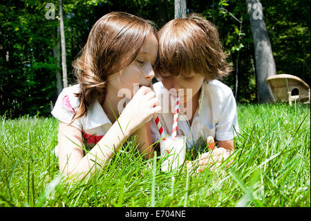 Brother and sister in woods sharing a milkshake Stock Photo