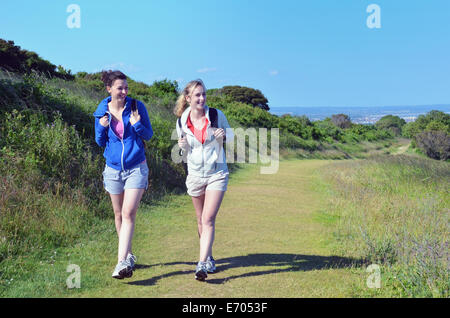 Two young women walking along coastal path Stock Photo