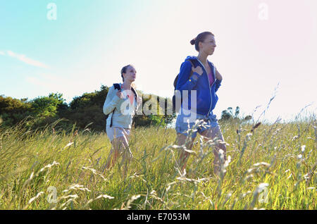 Two young women hiking through field Stock Photo
