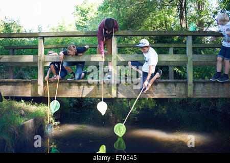 Boys using fishing nets on bridge Stock Photo