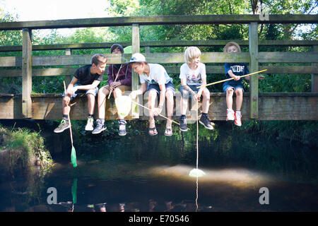 Boys sitting on bridge, fishing Stock Photo