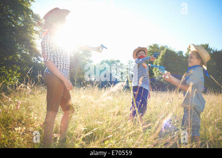 Three young boys dressed as cowboys, holding toy guns Stock Photo