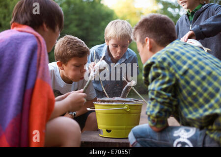 Young boys cooking fish over barbecue Stock Photo