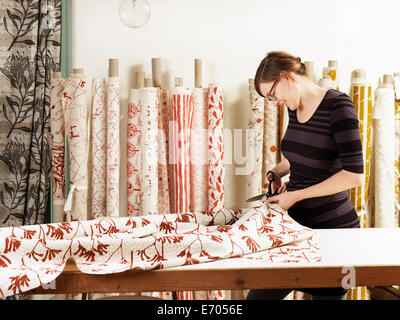 Woman cutting fabric on work table in hand-printed textile workshop Stock Photo