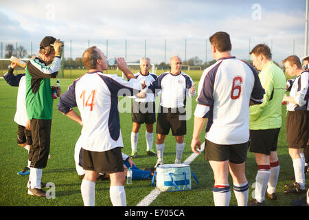 Football players resting and hydrating at half time Stock Photo