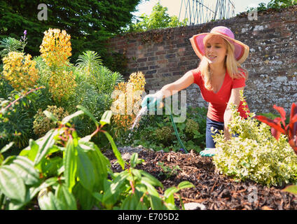 Young woman watering garden with hosepipe Stock Photo